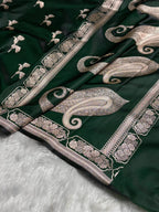 Green fabric with intricate silver embroidery on a white surface