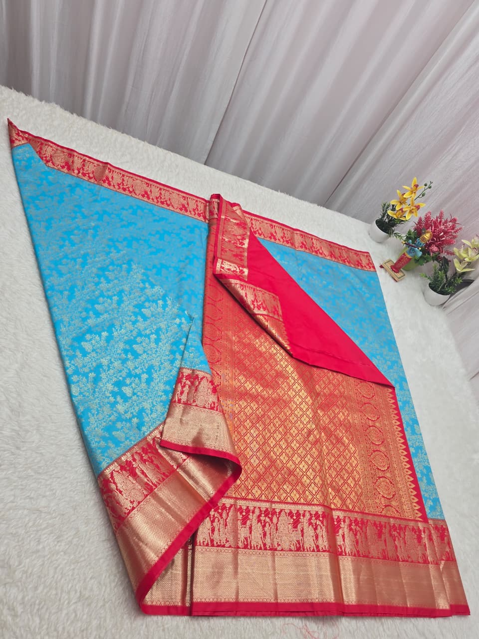 Traditional saree with blue, red, and gold patterns on a white surface.