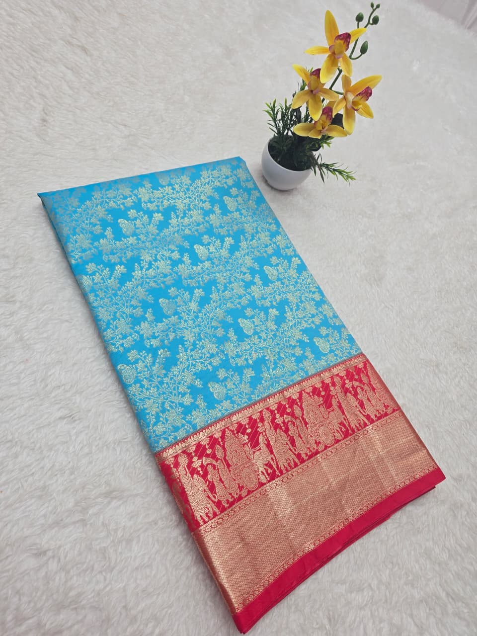 Blue saree with a red border on a light gray background