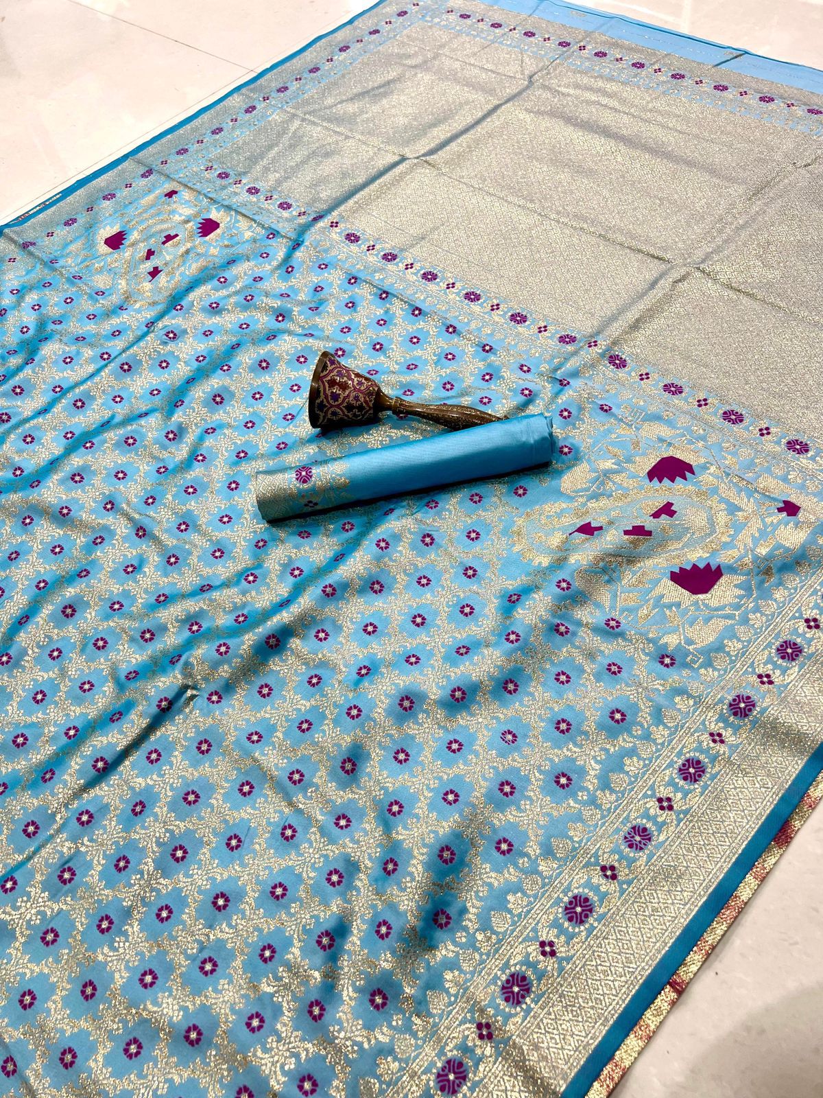 Blue floral patterned fabric with a rolled-up item on a tiled floor.