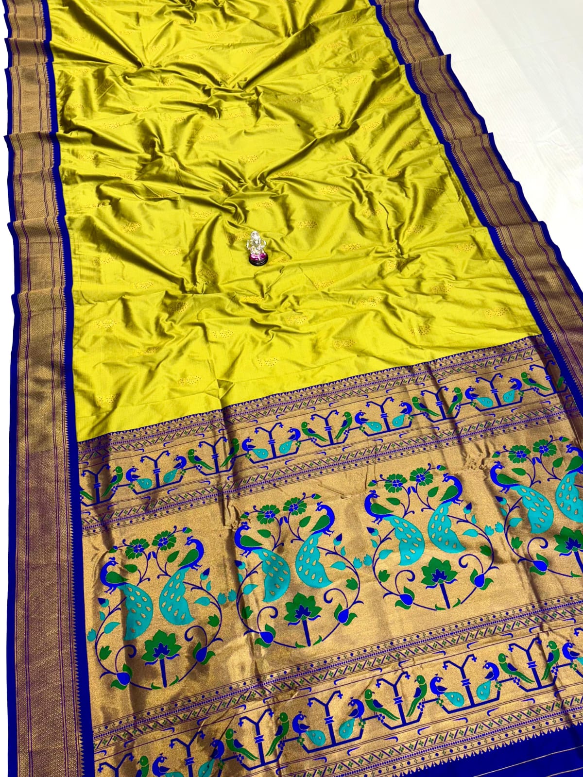 Yellow saree with blue and green peacock patterns on a white background