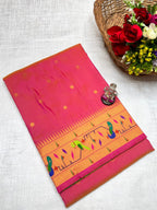 Pink and orange fabric with patterns on a white surface, next to a basket of flowers.