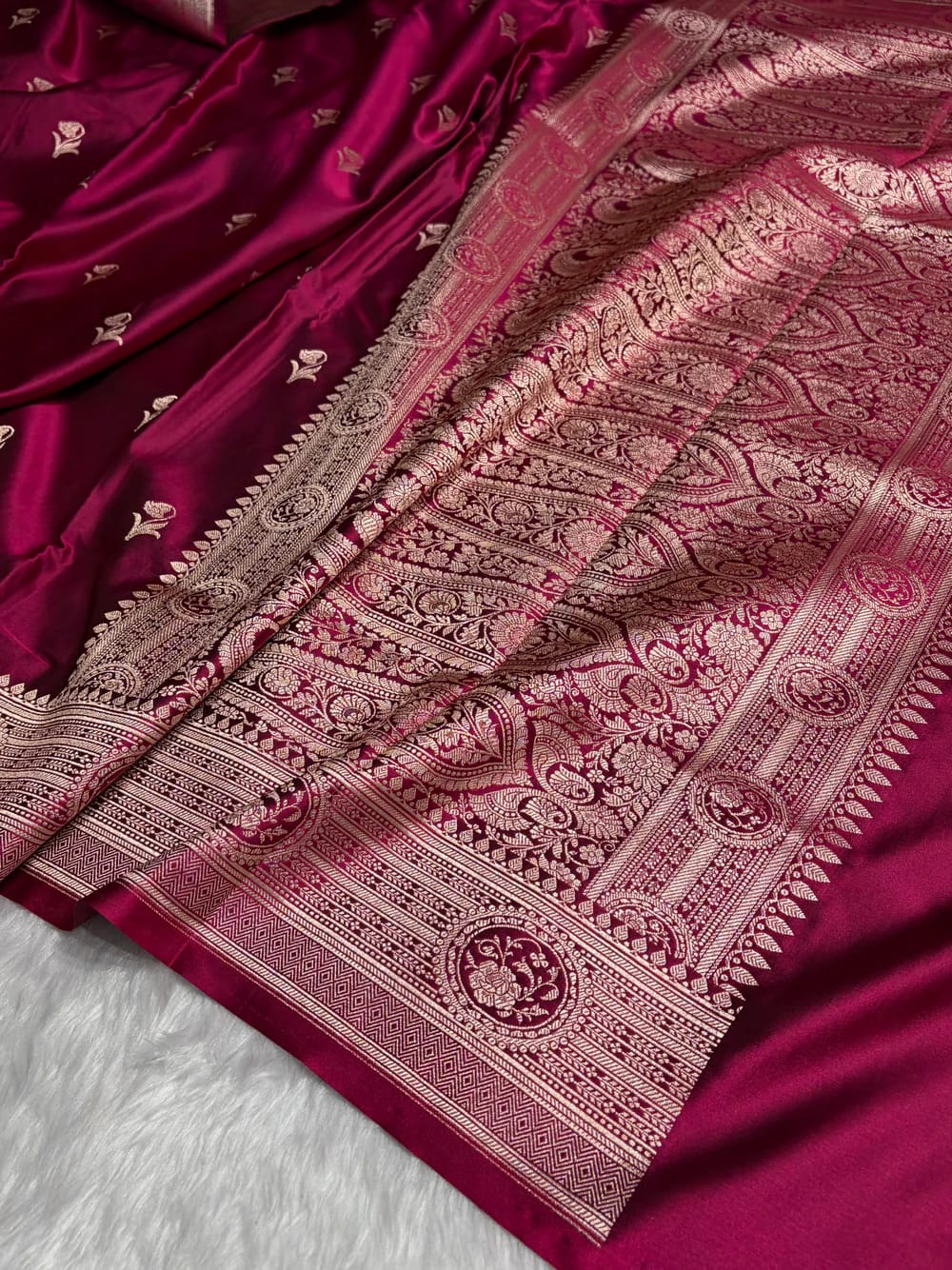 Maroon saree with intricate gold patterns on a white background
