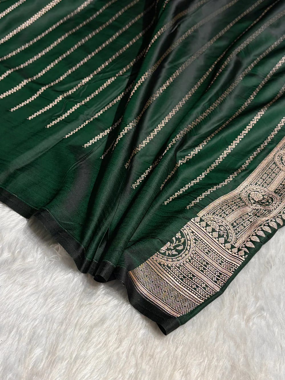 Green saree with intricate gold patterns on a white surface