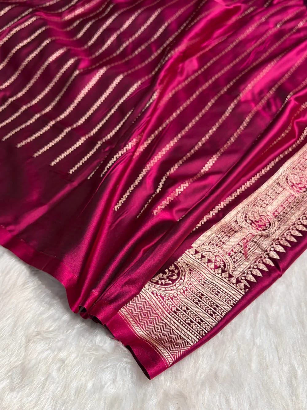 Close-up of a maroon fabric with intricate gold patterns on a white surface