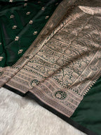 Close-up of a green saree with intricate gold patterns on a white surface