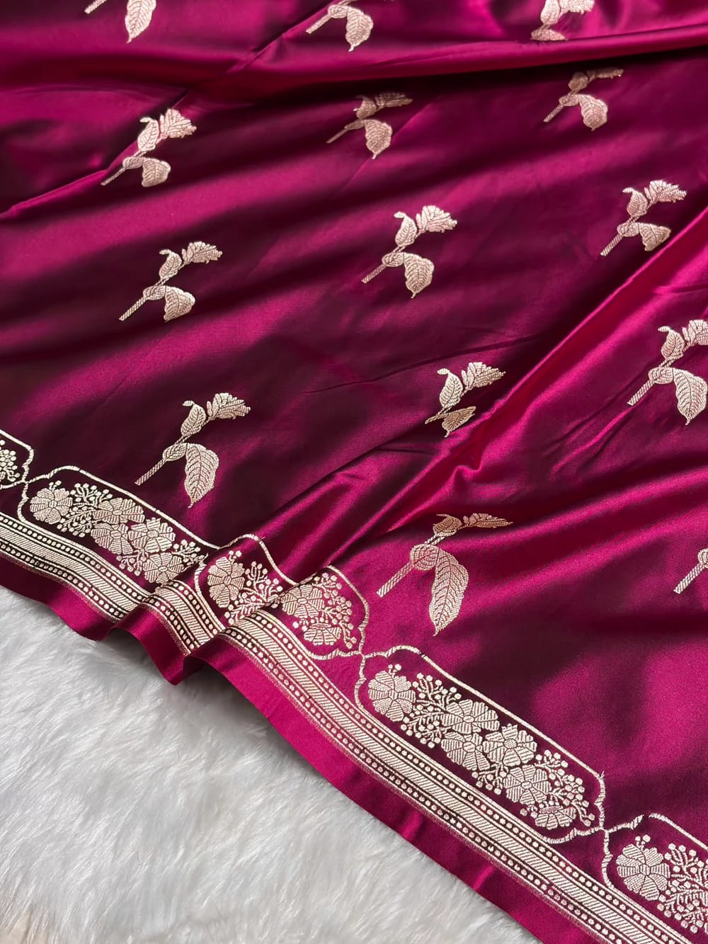 Close-up of a maroon fabric with gold embroidery on a white surface