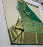 Green and beige saree with floral decorations on a white surface
