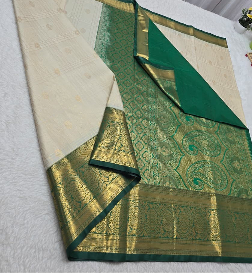 Green and beige saree with floral decorations on a white surface