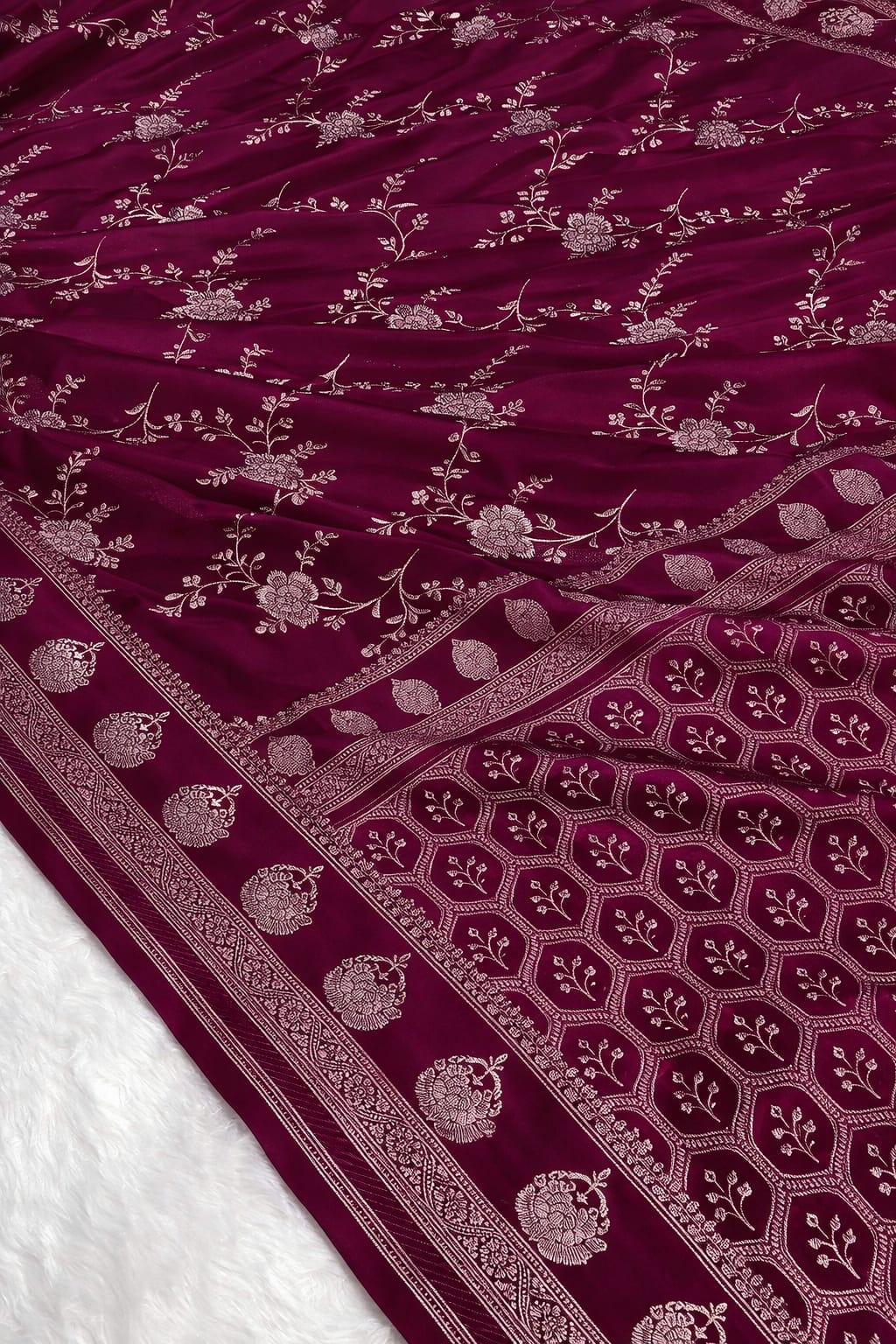 Maroon fabric with intricate silver patterns on a white background