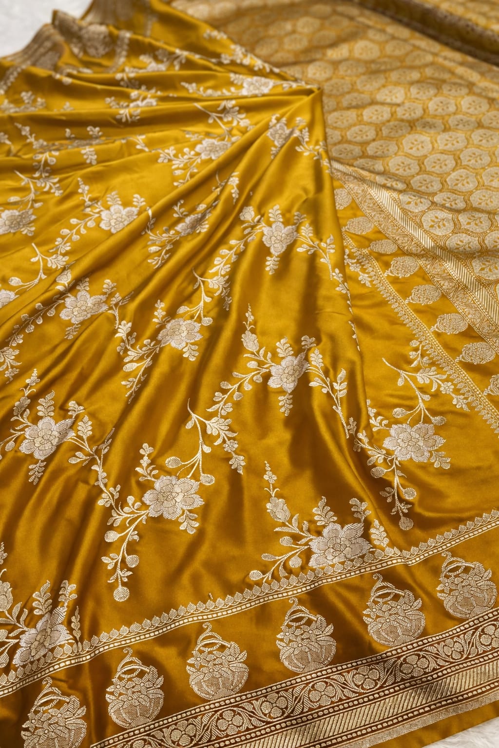 Mustard yellow fabric with intricate white floral embroidery and border details.