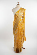 Yellow saree with white floral patterns on a dark surface