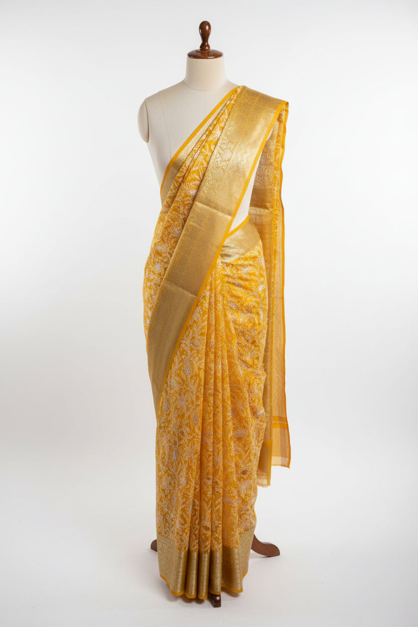 Yellow saree with white floral patterns on a dark surface