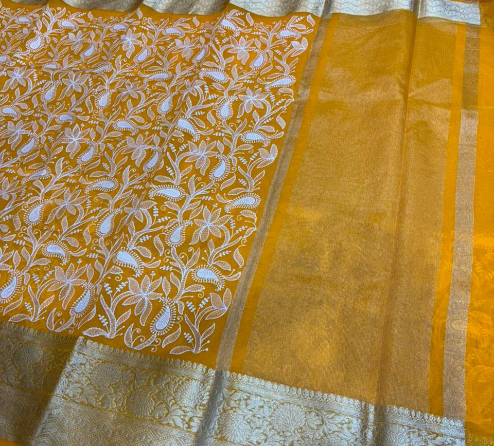 Yellow saree with white floral patterns on a dark surface