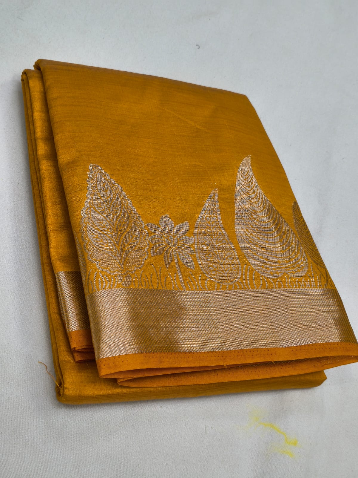 Mustard yellow saree with white embroidery on a white background