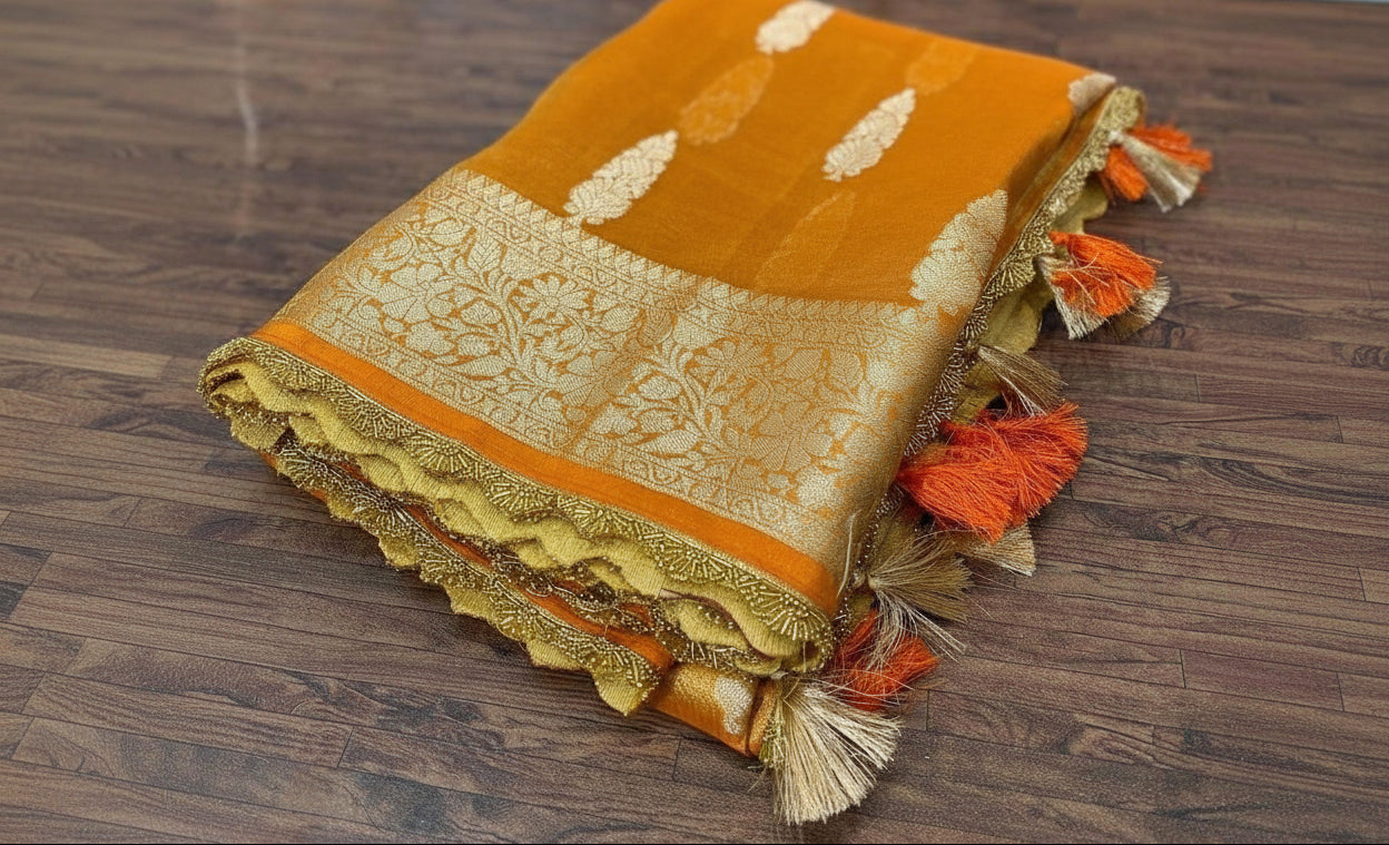Orange and gold fabric with tassels on a wooden surface