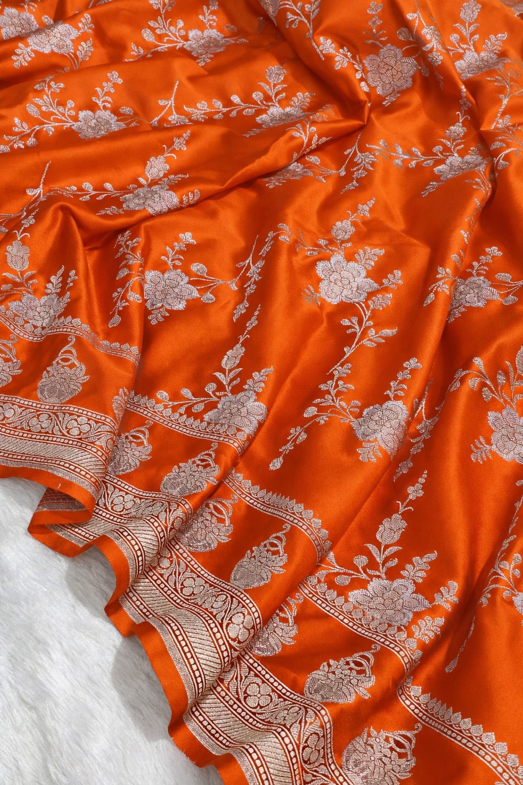 Orange fabric with intricate white patterns on a white background