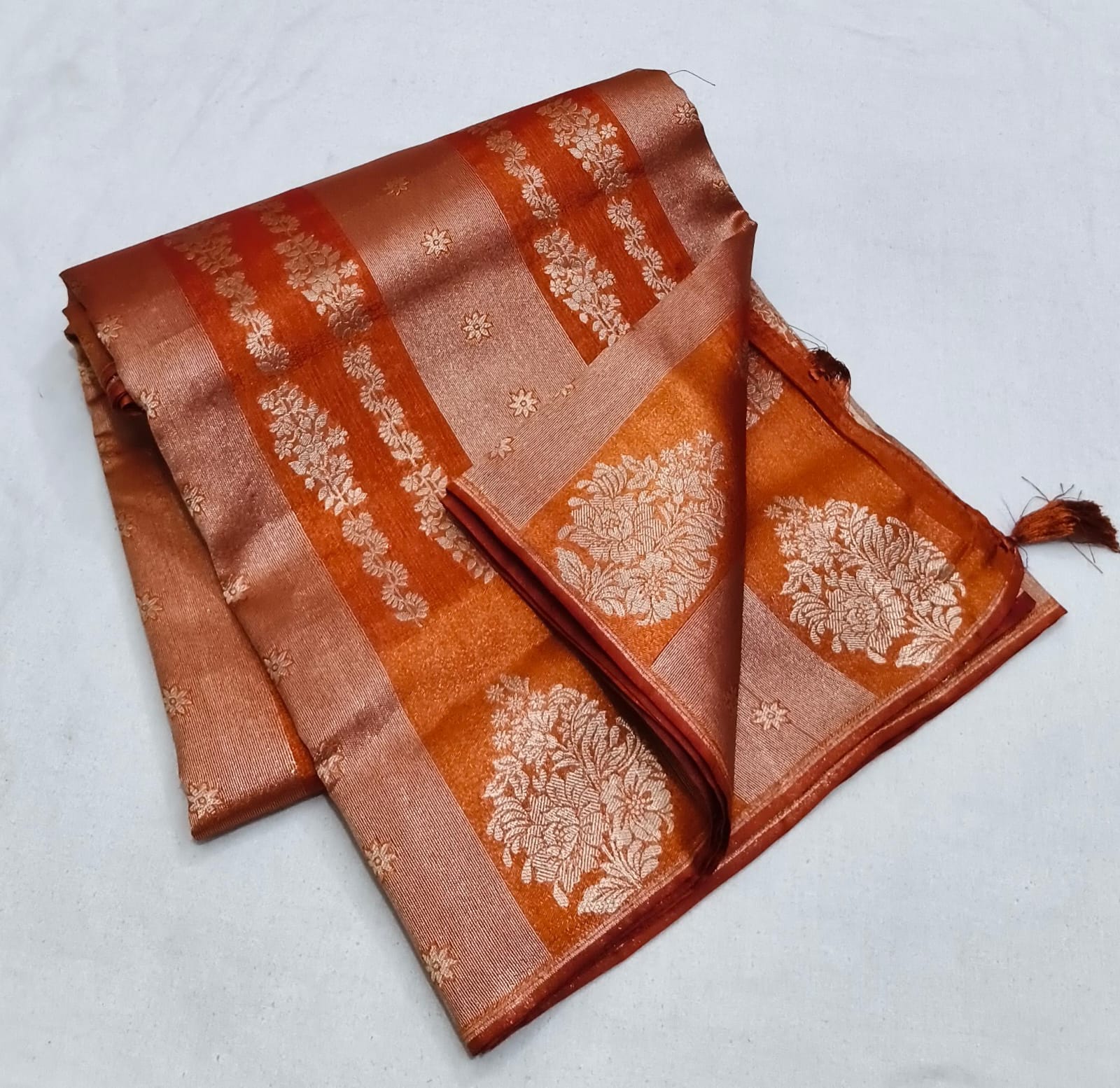 Brown saree with floral patterns on a light gray background