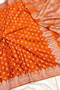 Orange saree with white patterns and gold border on a white background