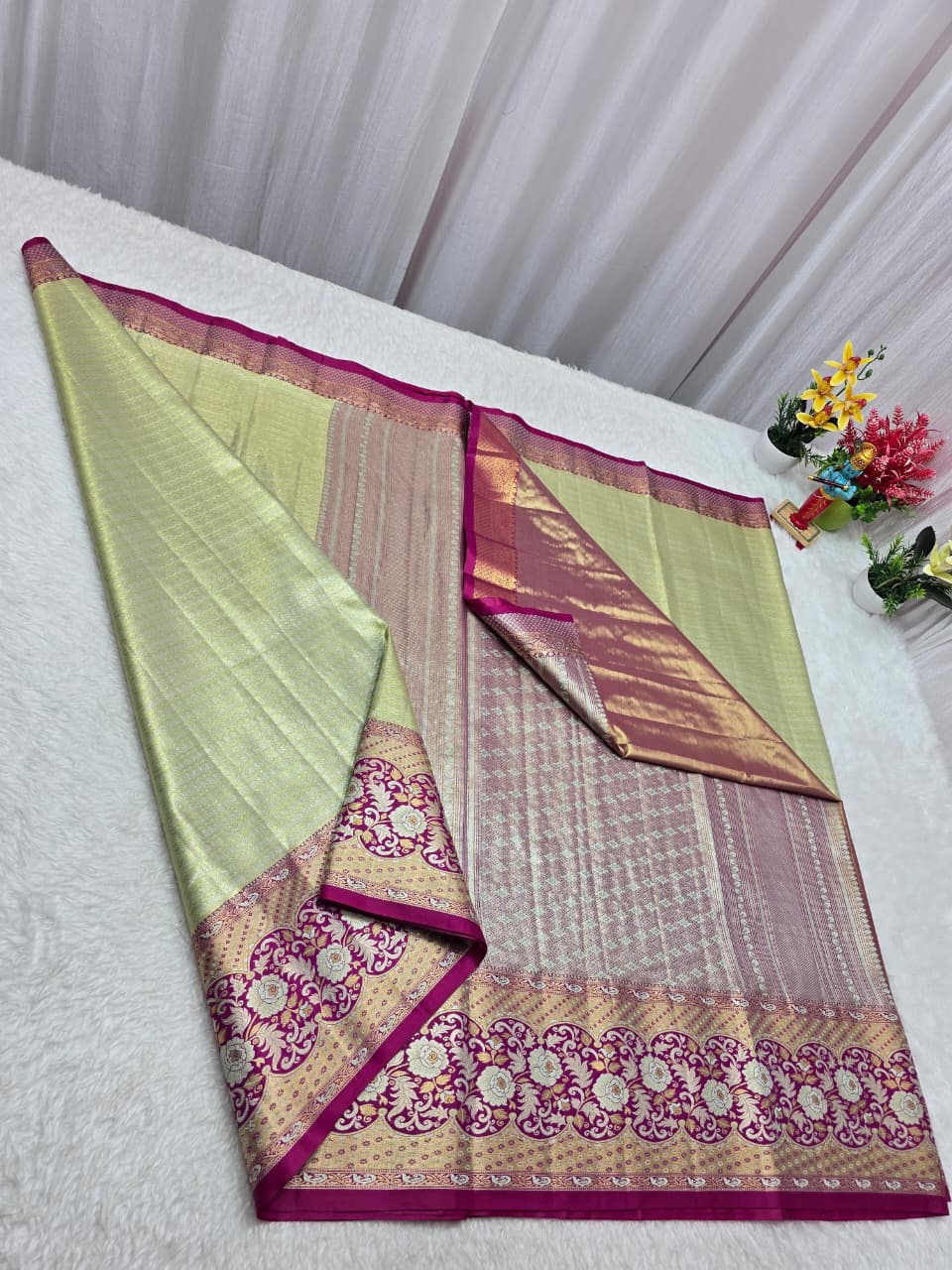 Saree with pink and green border on a white surface
