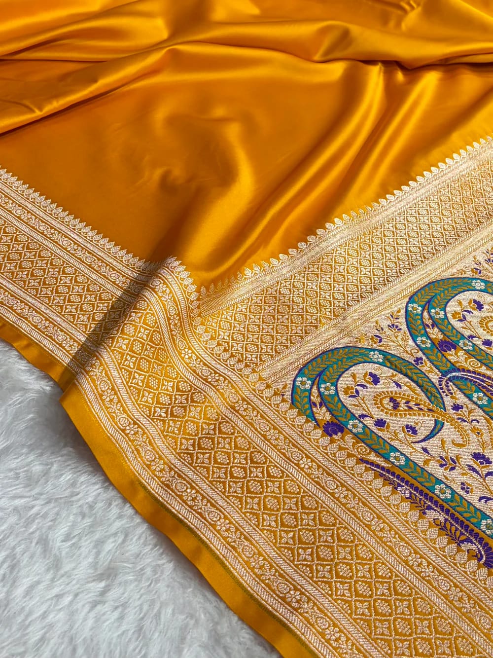 Close-up of a yellow saree with intricate patterns on a white background