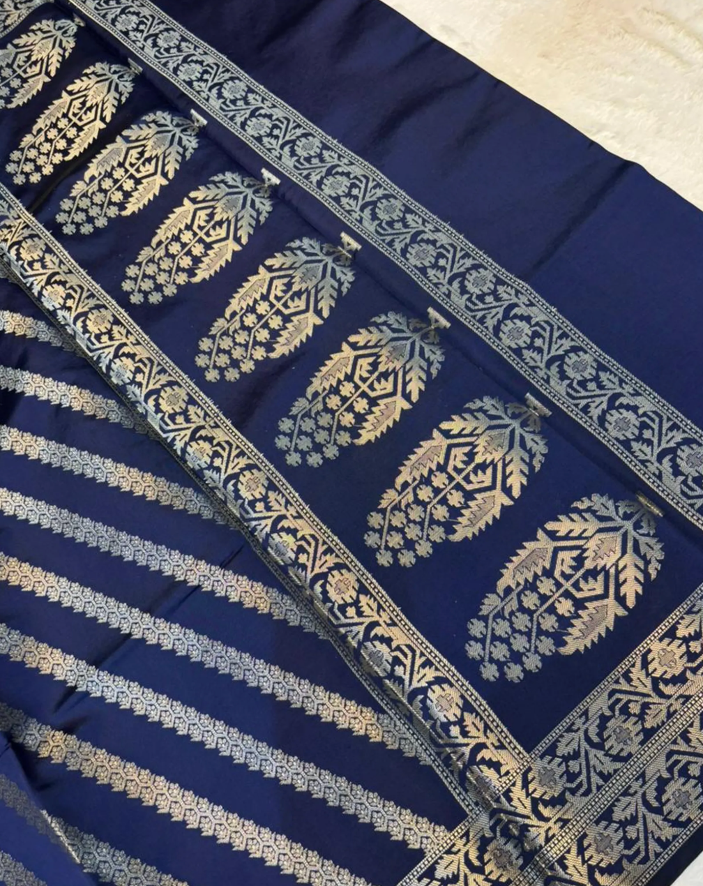 A close-up of a navy blue fabric textile with metallic gold block-printed motifs, including a border pattern and horizontal striped sections.