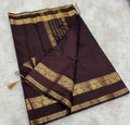 Brown saree with gold border on a tiled floor