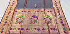 Traditional saree with intricate patterns on a table with stacks of fabric in the background