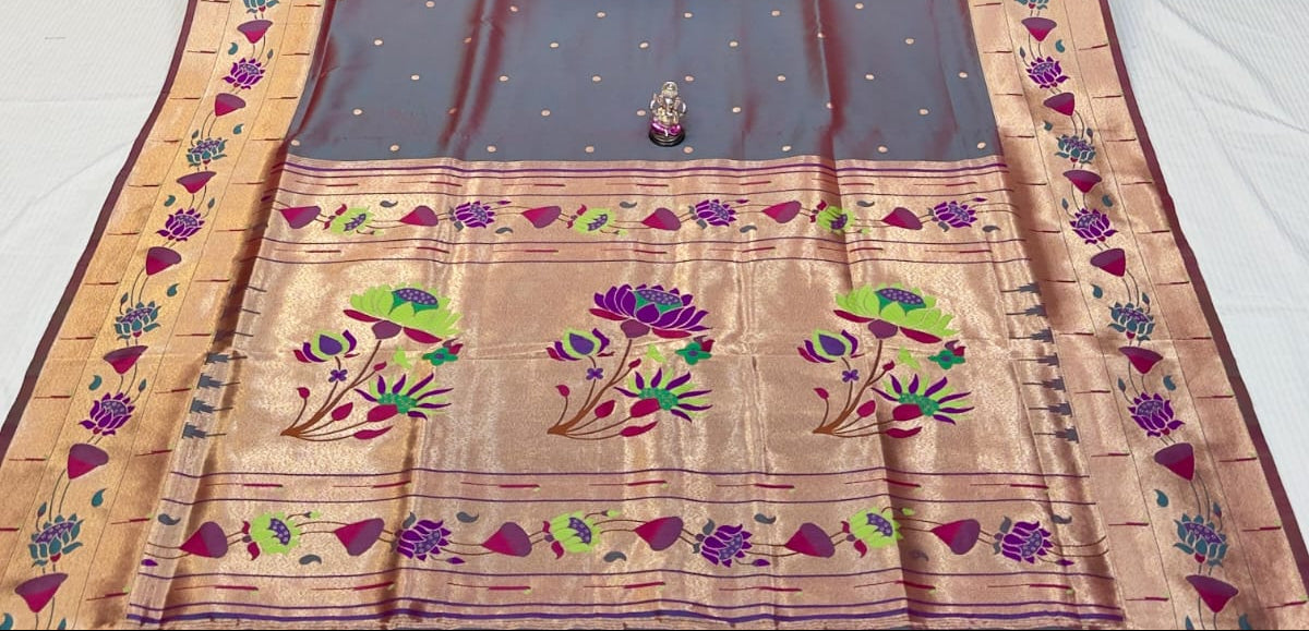 Traditional saree with intricate patterns on a table with stacks of fabric in the background