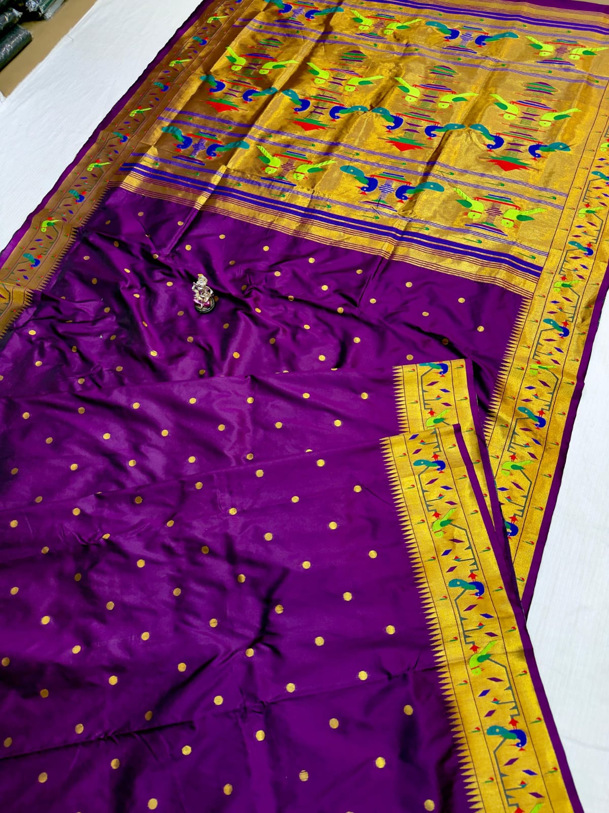 Purple saree with gold and multicolor border on a white background