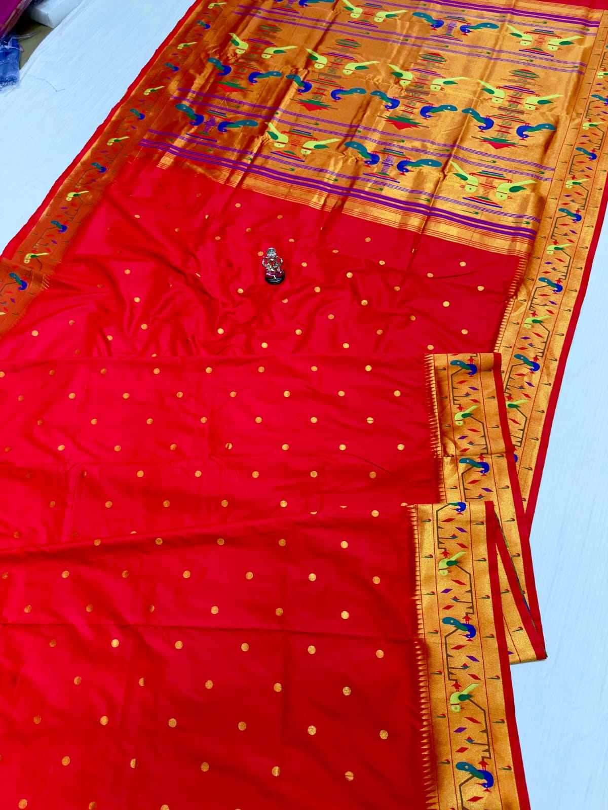 Red saree with gold patterns and a yellow border on a white background