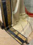 Traditional saree with gold and black border on a textured surface
