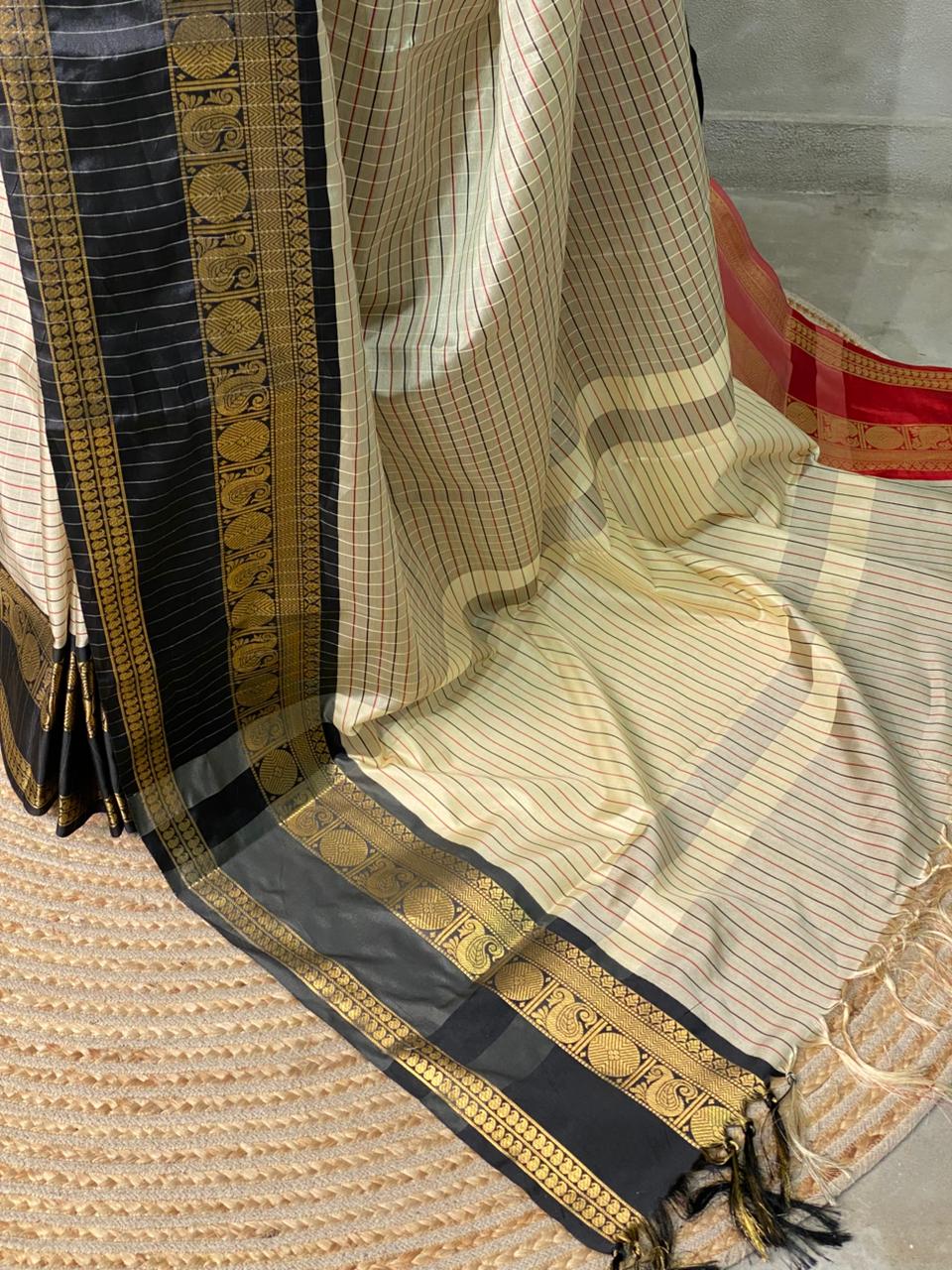 Traditional saree with gold and black border on a textured surface