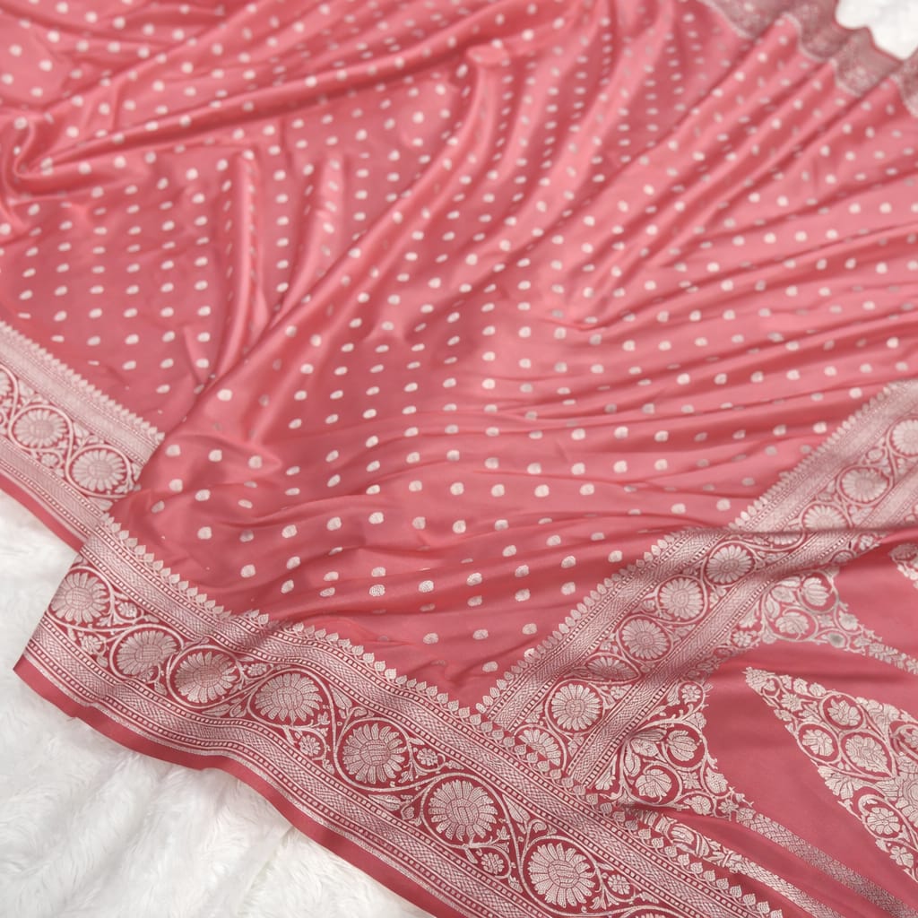 Pink saree with white polka dots and intricate border on a white background