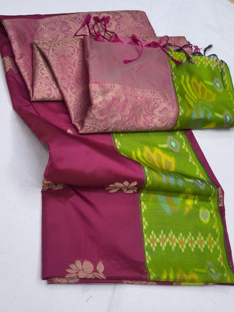 Pink and green saree with floral and geometric patterns on a white background