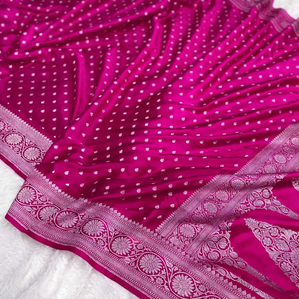 Pink saree with white polka dots and intricate border on a white background