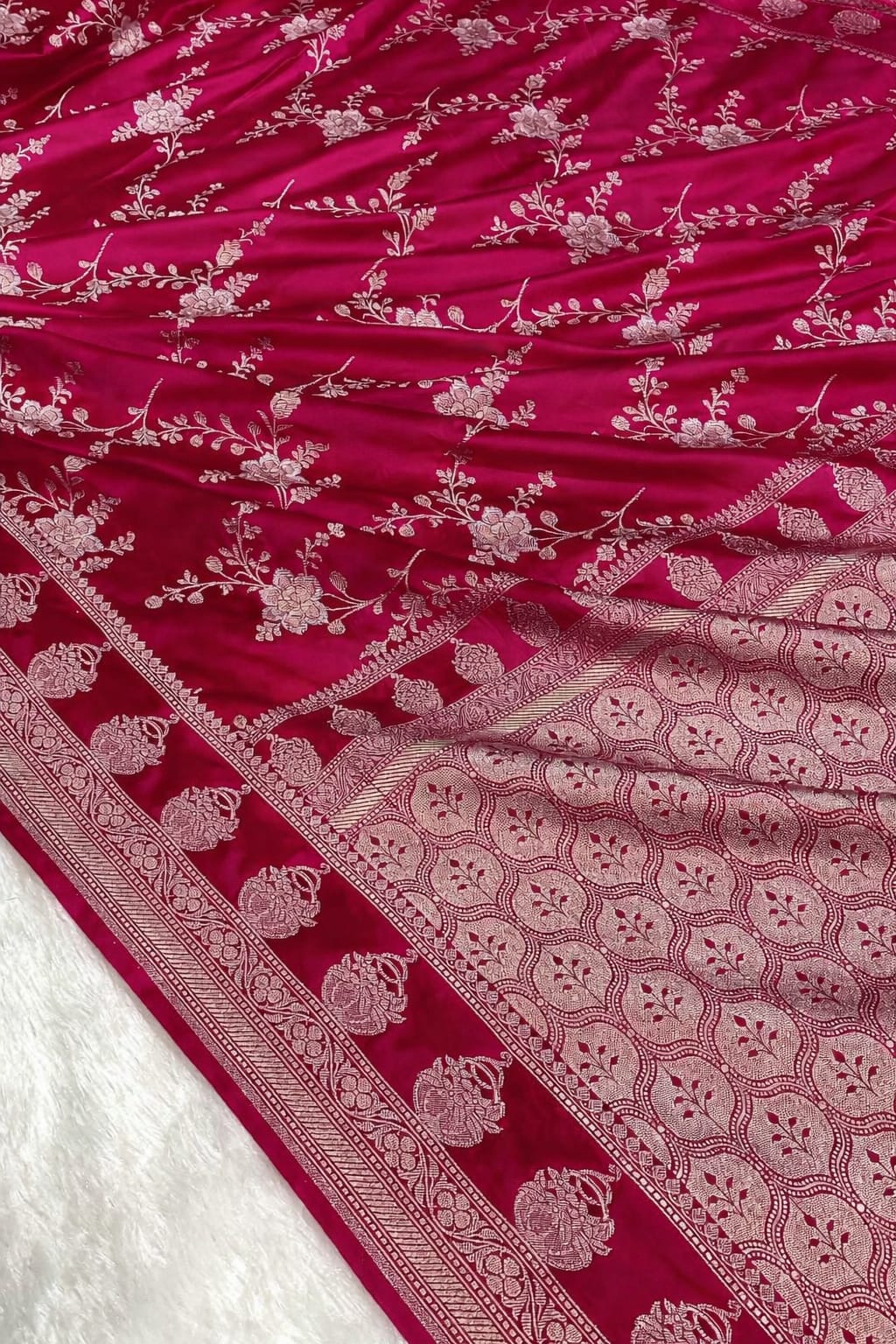 Pink fabric with white floral patterns and intricate border on a white background