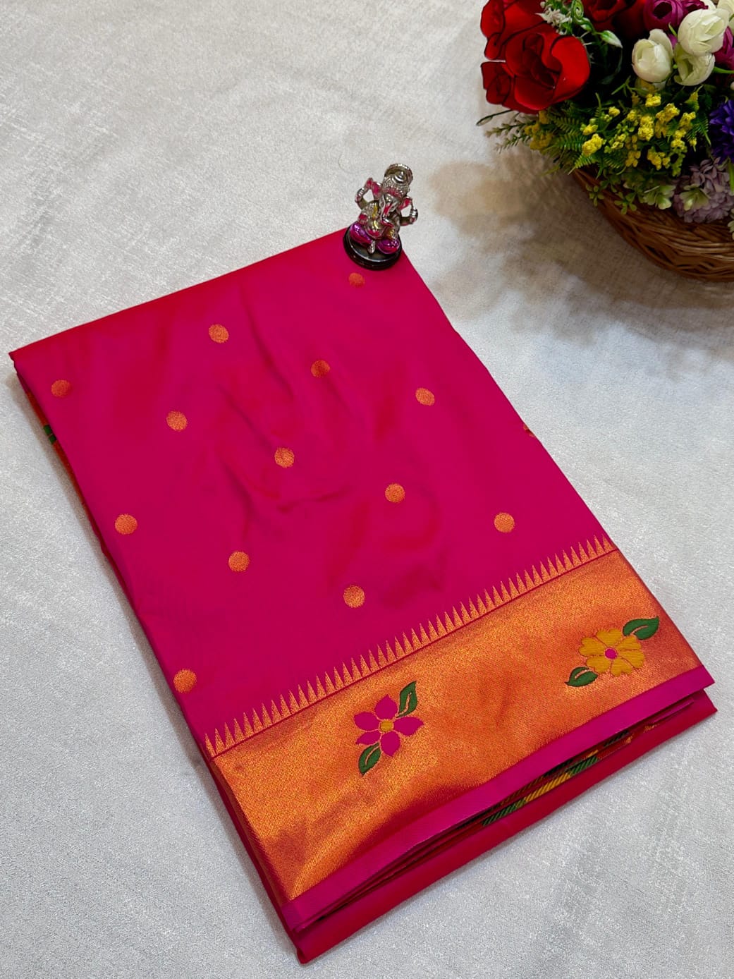 Pink and orange saree with floral patterns on a light gray surface