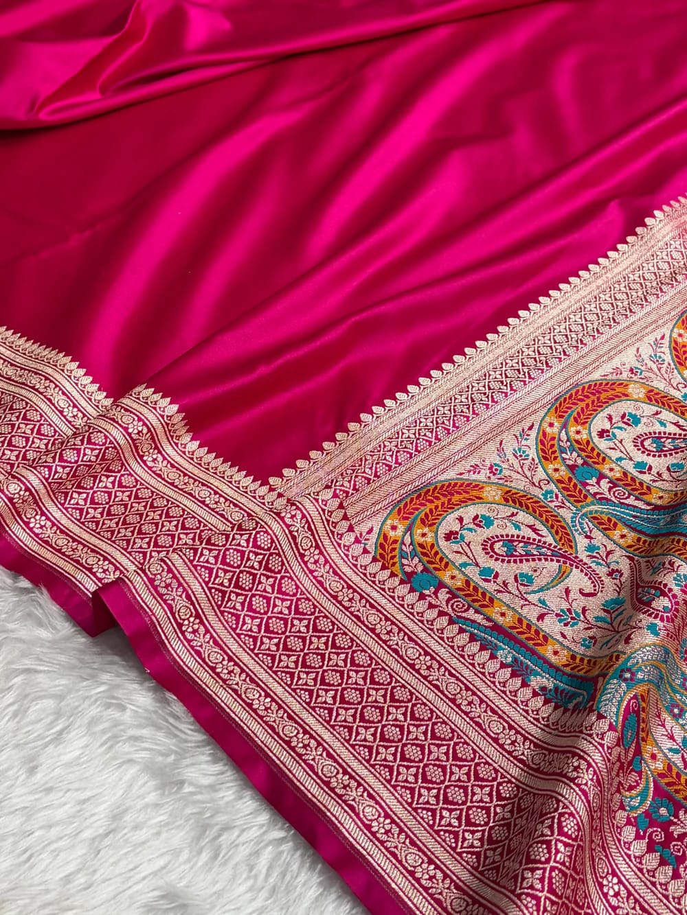 Pink fabric with intricate paisley patterns on a white background
