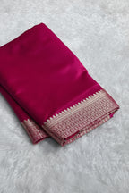 Pink saree with a decorative border on a light gray surface