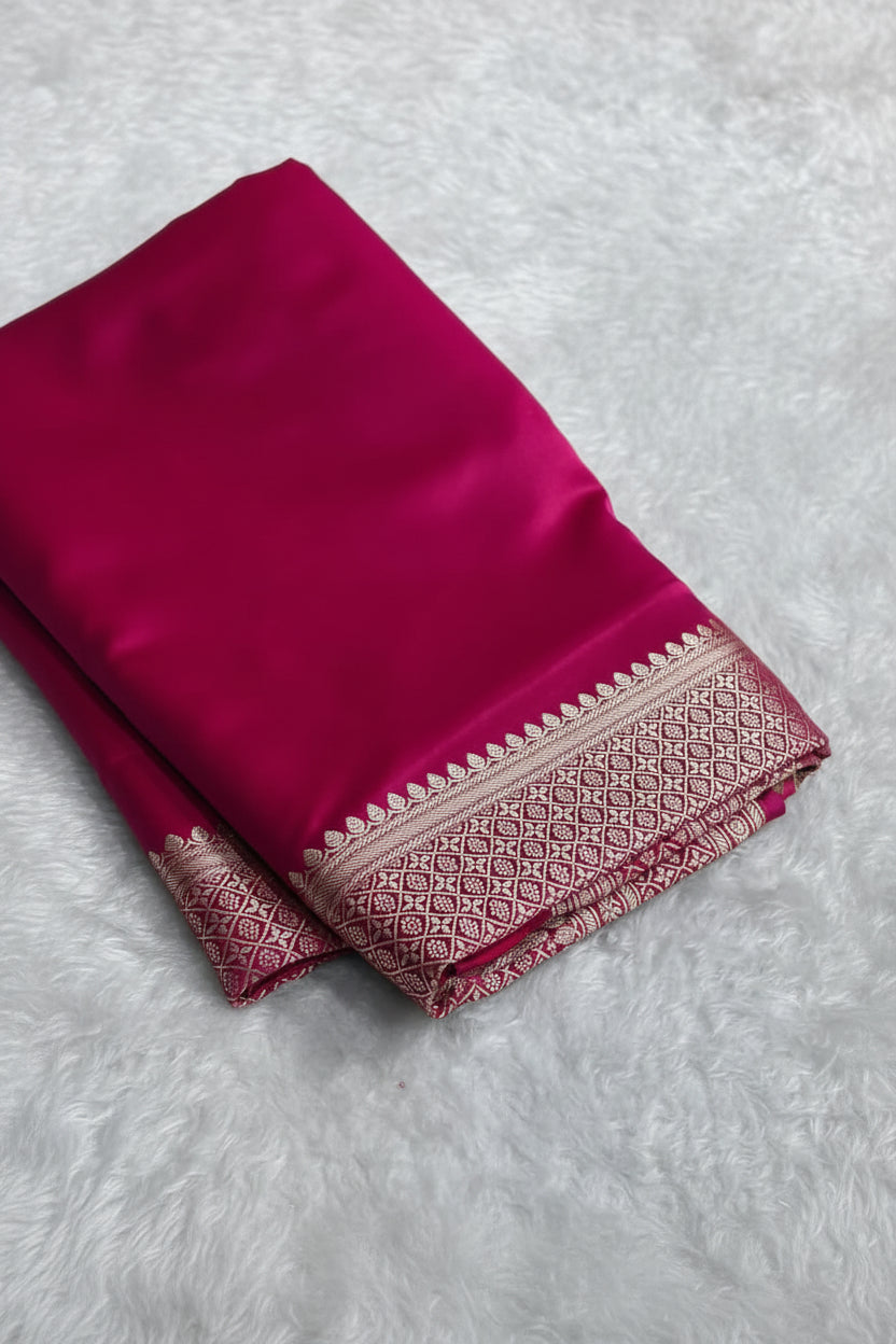 Pink saree with a decorative border on a light gray surface