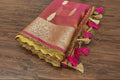 Decorative pink and gold fabric with tassels on a wooden surface