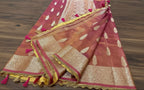 Decorative pink and gold saree with intricate patterns on a wooden surface.