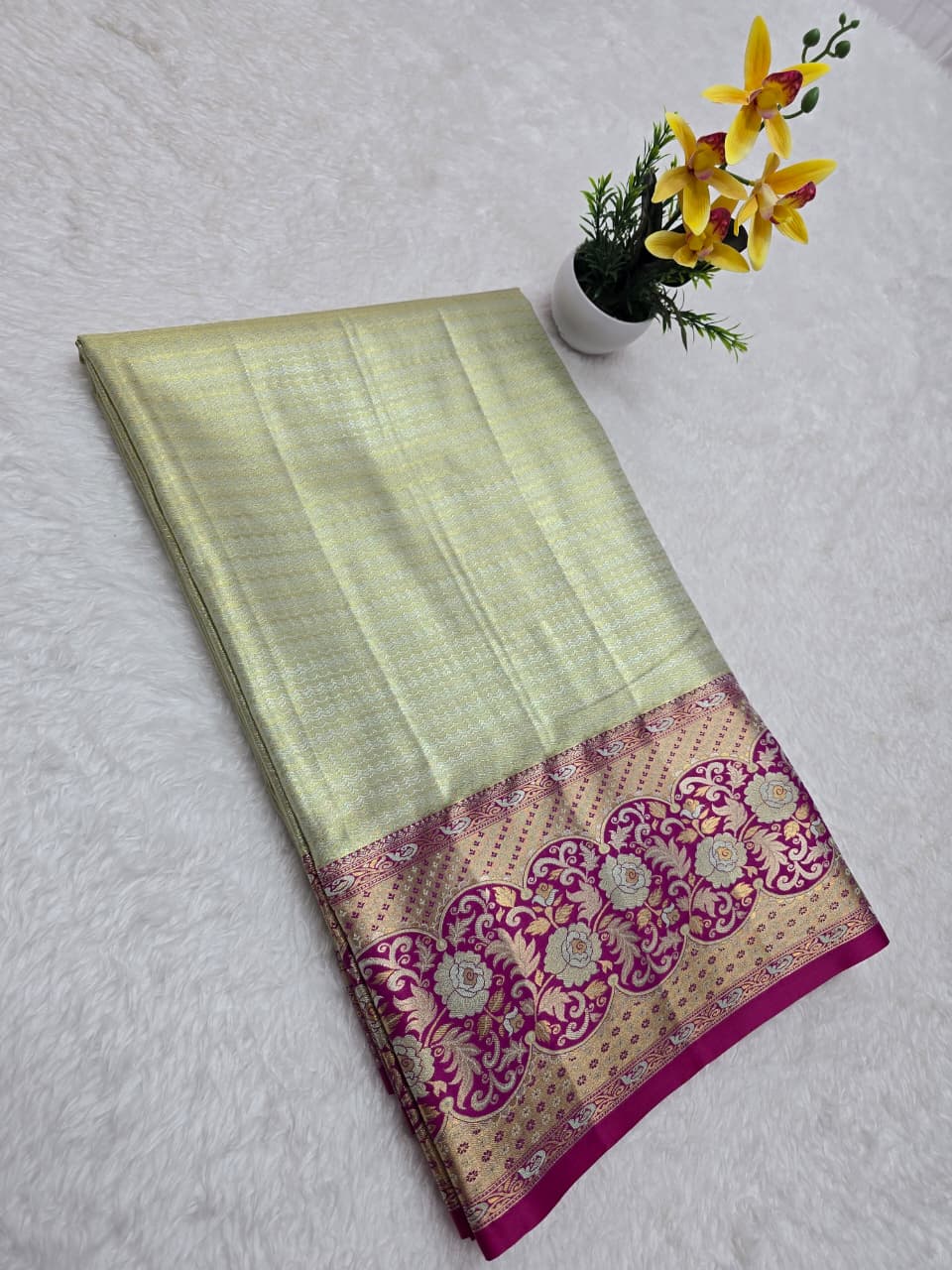 Light green saree with a pink and gold border on a white background