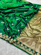 A green silk saree with gold zari embroidery, featuring small white floral motifs and a wide gold border.