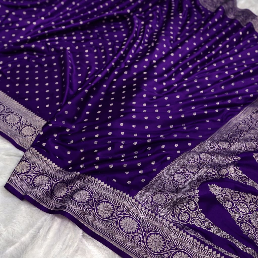 Purple saree with white polka dots and intricate border on a white background