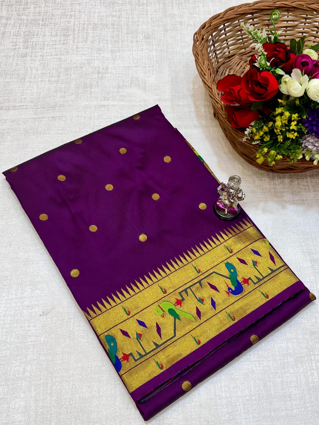 Purple saree with gold border and floral basket on a light gray background