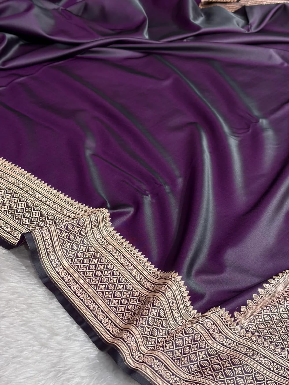 Purple fabric with intricate gold embroidery on a textured surface