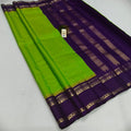 A folded purple and lime green silk saree with gold zari stripes and borders, displayed on a light gray background.