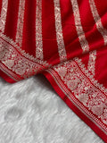 Red fabric with intricate white embroidery on a gray surface